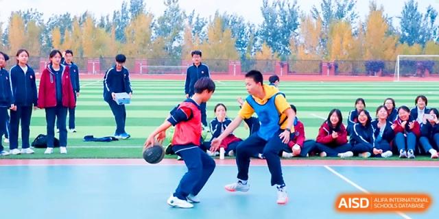 Two students compete for the ball during an intense basketball game on the outdoor court at Zibo International Academy At Hi-Tech Zone.