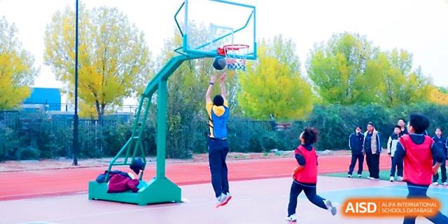 A student reaches high to shoot a basket during a physical education class at Zibo International Academy At Hi-Tech Zone.
