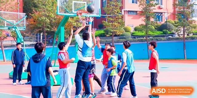 Students gather around the basketball hoop during an exciting outdoor tournament on the school courts at Zibo International Academy At Hi-Tech Zone.