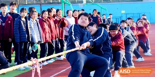A team of male students pulls with all their might during a competitive tug-of-war match on the track at Zibo International Academy At Hi-Tech Zone.