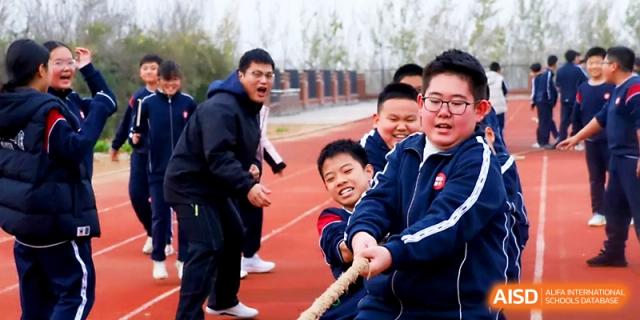Smiling students participate in a team tug-of-war competition, showing great school spirit at Zibo International Academy At Hi-Tech Zone.