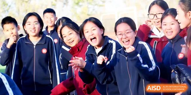 A group of female students smile brightly while cheering for their teammates during sports day at Zibo International Academy At Hi-Tech Zone.