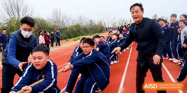 Students and staff members work together during a heavy-duty tug-of-war match on the running track at Zibo International Academy At Hi-Tech Zone.