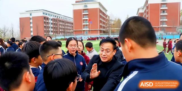A teacher or coach speaks to a group of attentive students during an outdoor sports event at Zibo International Academy At Hi-Tech Zone.