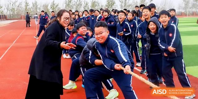 Students and a teacher pull the rope with determination during a tug-of-war competition at Zibo International Academy At Hi-Tech Zone.