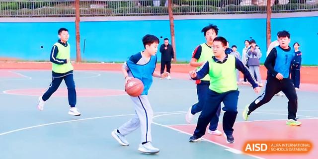 A young boy dribbles a basketball skillfully past opponents during an outdoor game at Zibo International Academy At Hi-Tech Zone.