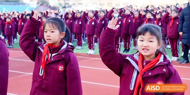 A young student raises her hand during a formal outdoor assembly with the student body at Zibo International Academy At Hi-Tech Zone.