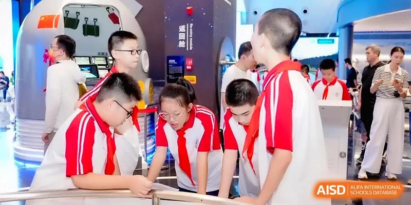 Four students in red and white uniforms lean in to closely examine a museum display during a trip for the Affiliated High School of Fujian Normal University.