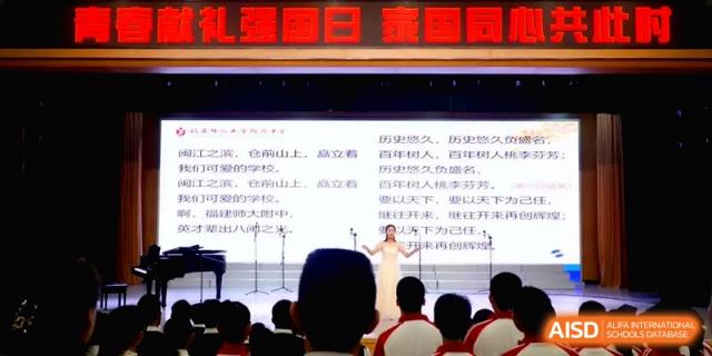 A soloist performs on stage in front of a screen with poetic text for the Affiliated High School of Fujian Normal University.