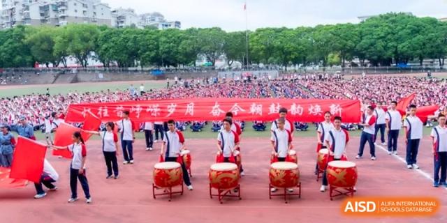Students play traditional drums in a synchronized performance on an outdoor field at the Affiliated High School of Fujian Normal University.