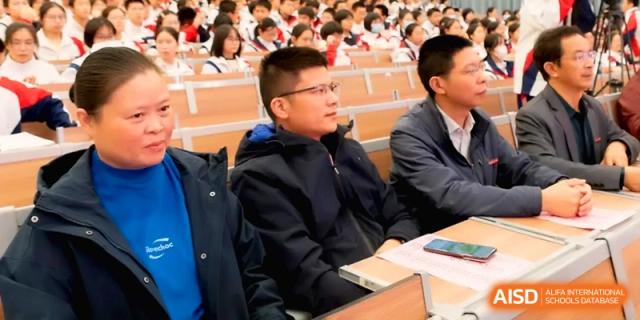 Men in jackets sit in a lecture hall during a formal meeting or seminar at the Affiliated High School of Fujian Normal University.