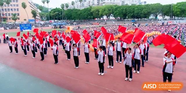 Students in white and red uniforms wave red flags in a line at the Affiliated High School of Fujian Normal University.