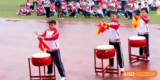 Two students in red and white uniforms play large traditional drums at the Affiliated High School of Fujian Normal University.