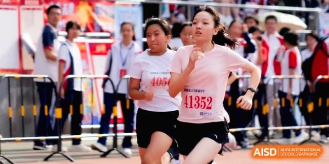Female athletes in pink shirts sprint toward the finish line on a track at the Affiliated High School of Fujian Normal University.
