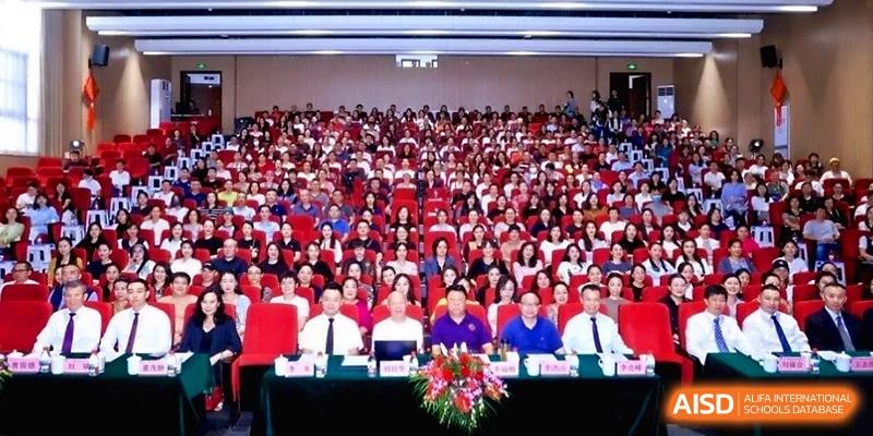 Wide shot of a large audience seated in an auditorium for a formal event or ceremony at the Affiliated High School Of Peking University Haikou.