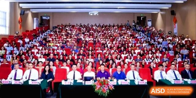 Wide shot of a large audience seated in an auditorium for a formal event or ceremony at the Affiliated High School Of Peking University Haikou.