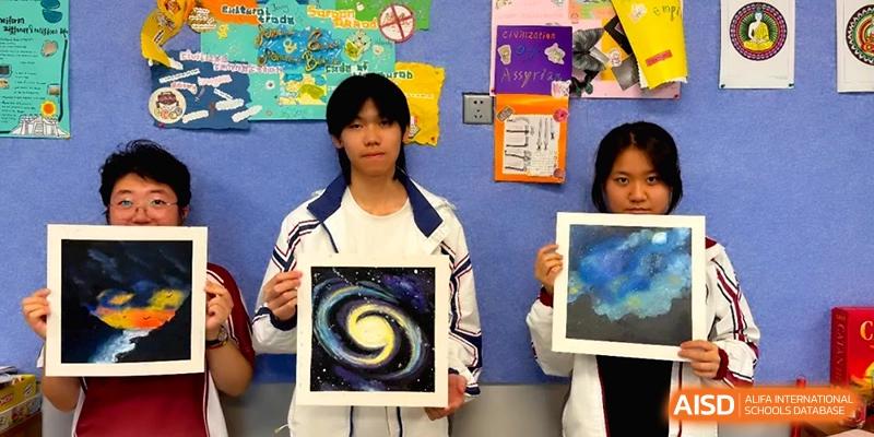 Students proudly displaying their colorful galaxy-themed artwork in a creative classroom at the Affiliated High School Of Peking University Haikou.