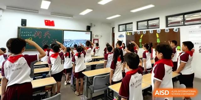 Students in uniforms stand at their desks during a lesson in a bright classroom at the Affiliated High School Of Peking University Haikou.