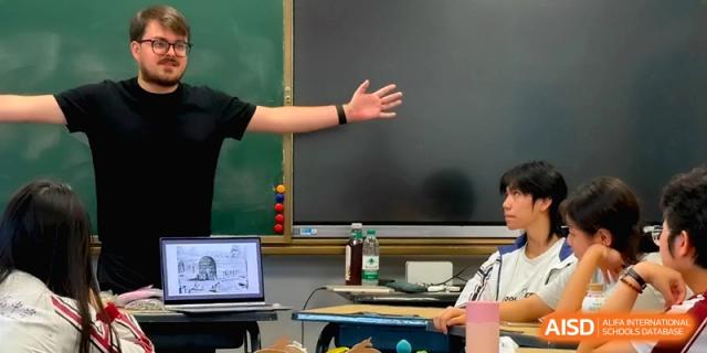 A teacher uses a digital screen and gestures toward the board during an interactive class at the Affiliated High School Of Peking University Haikou.