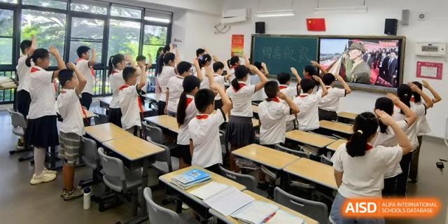 Students in a classroom raise their hands enthusiastically to participate in a lesson at the Affiliated High School Of Peking University Haikou.