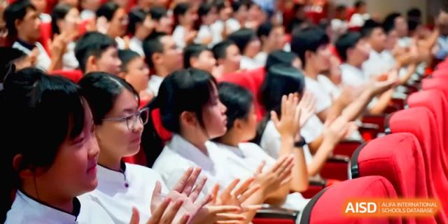 Students in white shirts clap their hands in unison during a celebratory school event at the Affiliated High School Of Peking University Haikou.