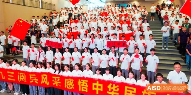 A large group of students stands in a tiered auditorium for a group photo at the Affiliated High School Of Peking University Haikou.