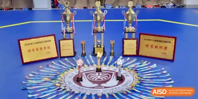 A display of gold trophies and awards won by the sports teams at the Affiliated High School Of Peking University Haikou.