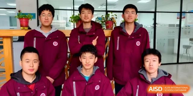 Four male students in matching maroon winter jackets pose together for a group photo in a bright hallway of the campus at Baoji Nanshan High School.