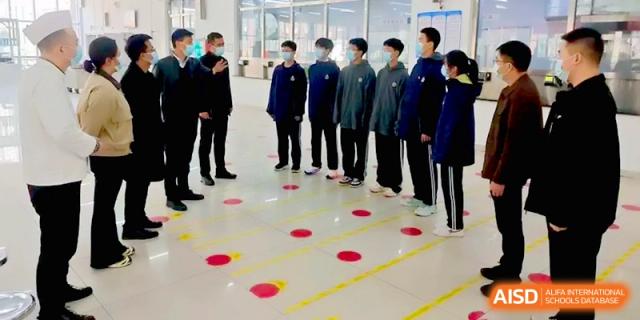 Students stand in organized rows on a floor marked with colored circles during a specialized training session at Baoji Nanshan High School.