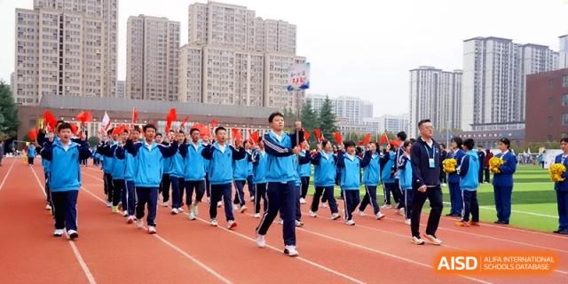 A massive formation of students in blue tracksuits marches in unison during an opening ceremony on the track at Baoji Nanshan High School.