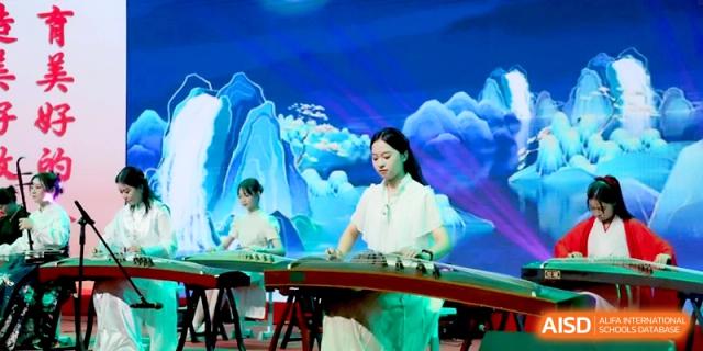 A young woman in traditional white attire plays a Guzheng stringed instrument on a stage with a blue backdrop at Baoji Nanshan High School.