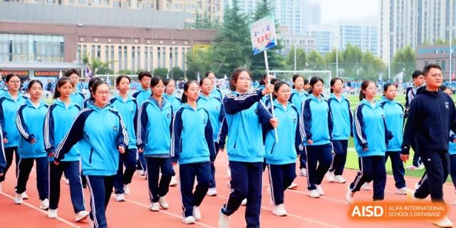 Students walk in formation while holding a placard during a sports day event held on the school's outdoor athletic grounds at Baoji Nanshan High School.