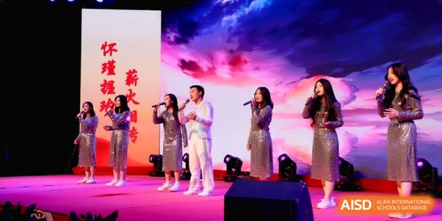 Four singers in elegant outfits perform together on a brightly lit stage under vibrant pink and purple lights at Baoji Nanshan High School.