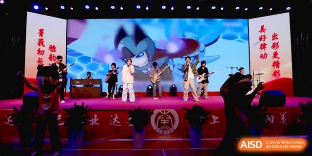 A student band featuring a lead singer and guitarists performs on stage with a large digital backdrop at Baoji Nanshan High School.