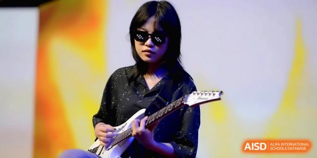 A student wearing sunglasses plays an electric guitar with confidence during a modern music performance on campus at Baoji Nanshan High School.