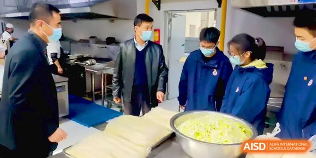 Staff and students inspect large containers of freshly prepared cabbage in the school's clean and organized kitchen at Baoji Nanshan High School.