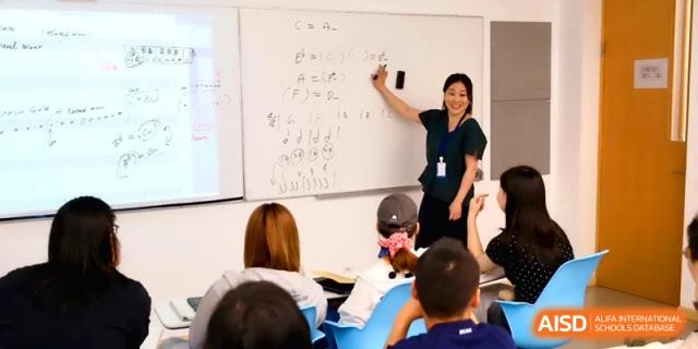 A music teacher stands at a whiteboard explaining musical notation to a class of students at Beijing Eastbank Academy of Music.