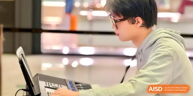 A close-up of a student wearing glasses while focused on playing an electronic keyboard at Beijing Eastbank Academy of Music.