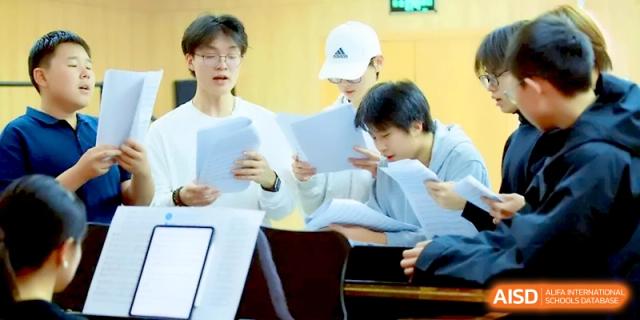 A group of students stands together holding and reading sheet music during a rehearsal at Beijing Eastbank Academy of Music.