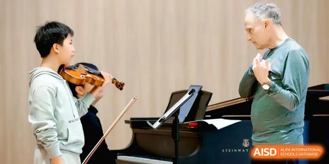 A student plays the violin alongside a grand piano during a practice session at Beijing Eastbank Academy of Music.