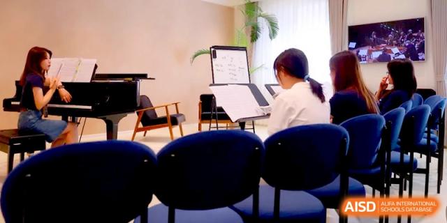 A student sits at a piano in a sunlit practice room with a music stand nearby at Beijing Eastbank Academy of Music.