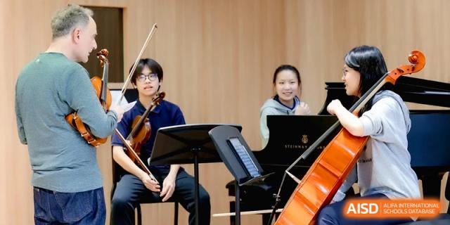 A young violinist and a cellist practice together in a wood-paneled music room at Beijing Eastbank Academy of Music.