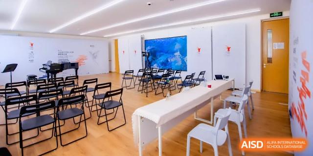 An empty modern recital room set up with rows of chairs and a long white table for an event at Beijing Eastbank Academy of Music.