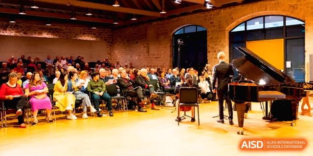A wide shot of an audience seated in a historic venue watching a live musical performance at Beijing Eastbank Academy of Music.