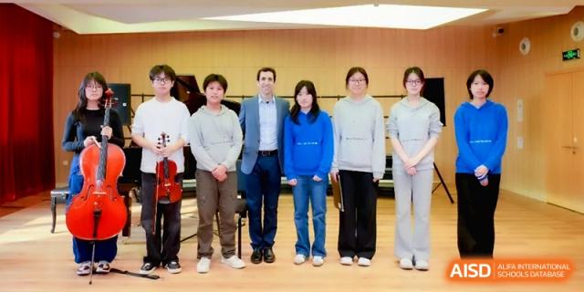 A group portrait of five students and one instructor standing together in a bright music studio at Beijing Eastbank Academy of Music.