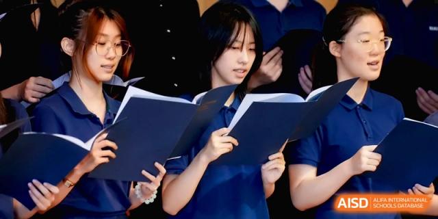 Close-up of a female student singing with a choir while holding a blue music folder at Beijing Eastbank Academy of Music.
