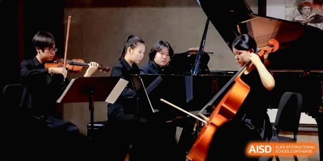 Students collaborating and practicing together at a grand piano in a rehearsal room at Beijing Eastbank Academy of Music.