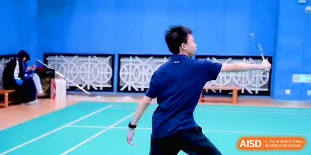 A student in a blue sports uniform playing a game on the indoor badminton courts at Beijing Eastbank Academy of Music.