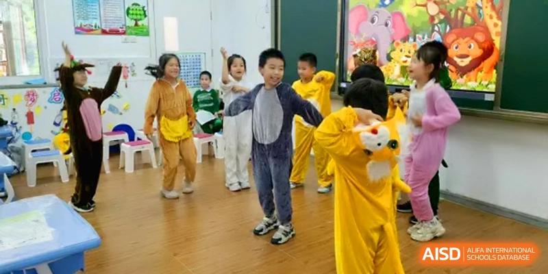 Children dressed in various animal costumes including lions and bears perform a lively dance routine on a wooden floor in a classroom at Beijing Haidian Rising Experimental School