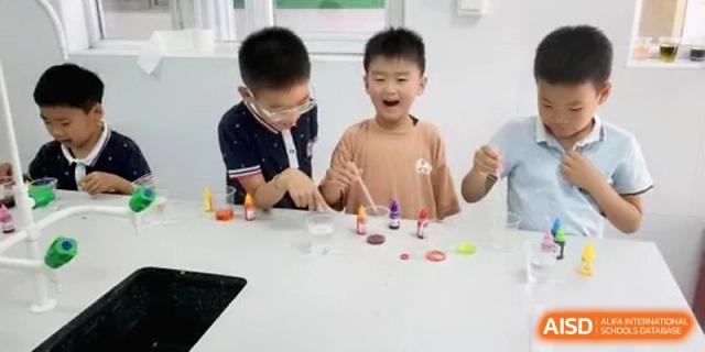 Two curious students conduct a colorful science experiment with liquids and droppers at a white lab table in a bright classroom at Beijing Haidian Rising Experimental School